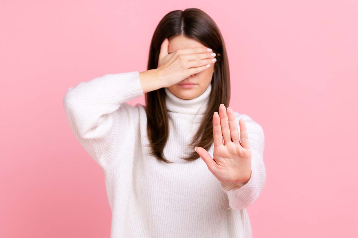 Woman covering her eyes and holding a hand up to indicate resistance to change