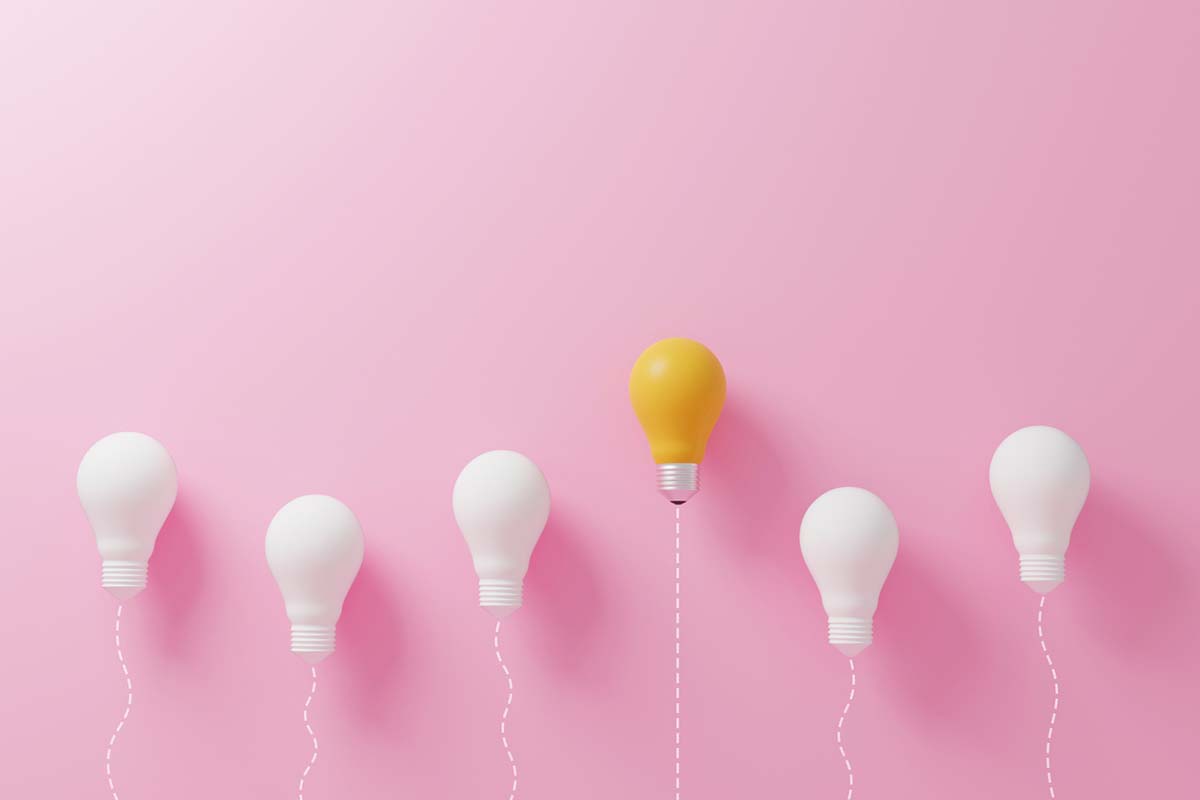 Yellow light bulb stands out among white light bulbs representing innovative marketing